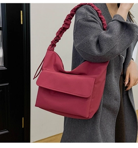 Detail of burgundy nylon crossbody bag with pleated strap and flap pocket for autumn wear