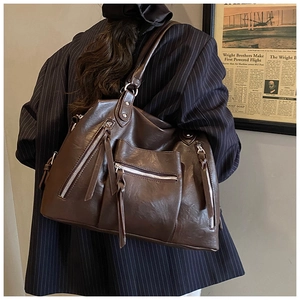 Detail view of large brown PU leather shoulder bag with tassels and metallic zippers