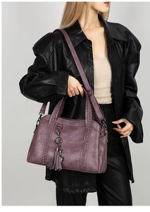 Detail of purple lychee grain leather tote with woven handles and cat charm tassel