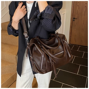 Detail of a brown PU leather shoulder bag featuring a side zipper and decorative tassel