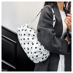 Vue détaillée du grand sac à pois noir et blanc sur un mannequin en manteau gris