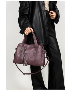 Detail of purple faux leather handbag featuring woven handles and stylish leather tassels