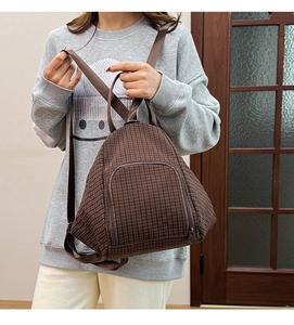 Detail of a brown plaid minimalist backpack in durable fabric with a zip front pocket