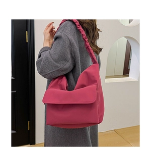 Detail of fuchsia nylon crossbody bag with pleated strap worn on a dark wool coat