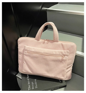 Detail of pink corduroy laptop bag showing dual metal zippers and durable fabric texture