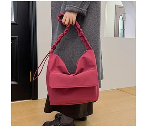 Detail of fuchsia nylon tote with cloud-like ruched handles and front flap pocket