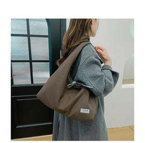 Brown canvas tote bag detail featuring the white 'FASHION INSTINCT' woven side label