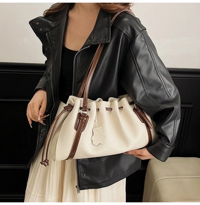 Detail of cream pleated tote bag with drawstring closure and cute bear charm pendant