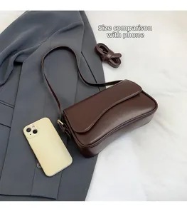 Deep brown rectangular shoulder bag size comparison with phone on grey suit background