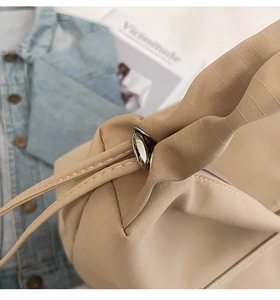 Detailed close-up of beige quilted nylon fabric texture with metallic lock and drawstring