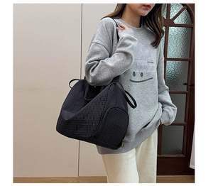 Detail view of large checkered shoulder bag showing side shoe compartment and canvas texture