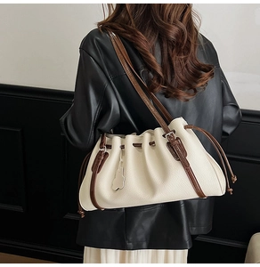 Detail view of the vintage pleated tote bag with dark brown straps worn over a leather jacket