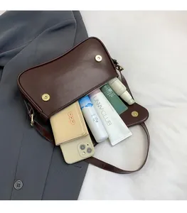 Detail view of the spacious interior of a brown leather shoulder bag holding daily essentials