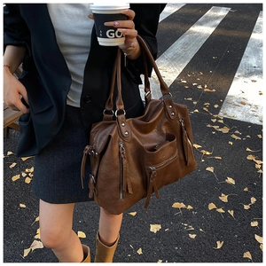 Street style shot of large brown PU leather tote bag with zippers and metal rivets