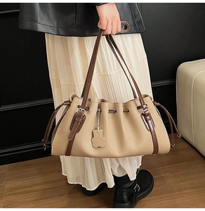 Detail of beige pleated tote bag with dark brown strap and cute bear charm pendant