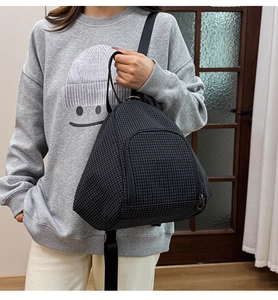 Detail of lightweight black mesh backpack showing the zip pocket and triangular silhouette