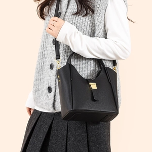 Sac seau noir en cuir litchi avec fermoir doré porté à l'épaule par un mannequin femme