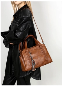 Macro shot of vintage brown leather handbag with woven handle and tassel charm