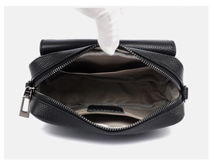 Interior detallado del bolso bandolera de cuero negro con bolsillo con cremallera y forro