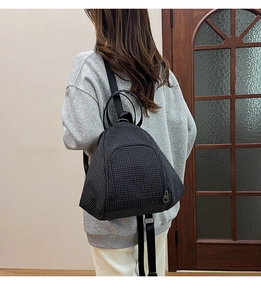 Detail of black checkerboard backpack showing triangular design and canvas texture on model