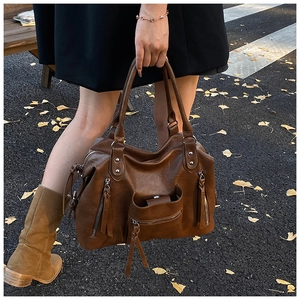 Retro brown PU leather tote bag with tassel details shown in a dynamic street style setting