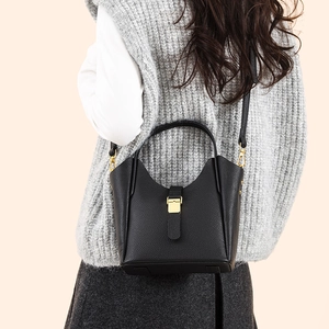 Détail du sac seau noir en cuir grainé avec boucle dorée et bandoulière élégante