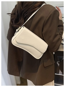 Detail showing the cream white shoulder bag with unique wave flap design on a model