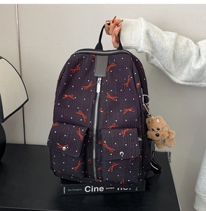 Détail d'un sac à dos froissé avec motifs de nœuds et breloque petit chien en peluche