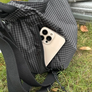 Détail de la poche latérale zippée d'un sac en toile à carreaux noir avec un smartphone