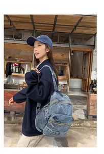Détail d'un sac à dos vintage en jean bleu avec bretelles réglables porté par un modèle