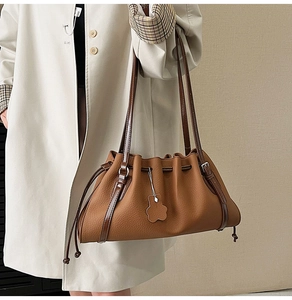 Detail showing the brown pleated tote bag with drawstring closure and cute bear pendant