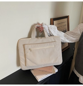 Close-up of cream corduroy laptop bag with double zippers and reinforced handle