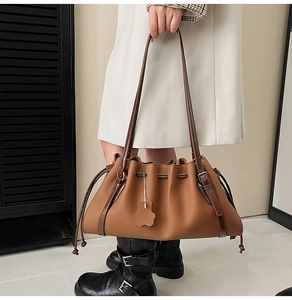 Detail of vintage brown leather tote bag showing pleats and flower charm ornament