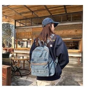 Détail d'un sac à dos en denim délavé bleu foncé porté dans un café accueillant