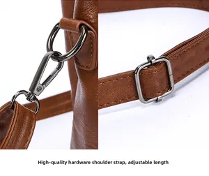 Detail view of brown PU leather bag with dark grey metal hooks and adjustable strap