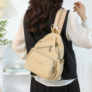 Détail du sac de poitrine en toile beige avec fermetures éclair et texture tissée