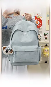 Close-up of light blue casual backpack with white bow patterns and a dog keychain