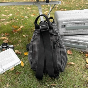 Détail du sac bandoulière en toile à carreaux sur une table de camping en plein air