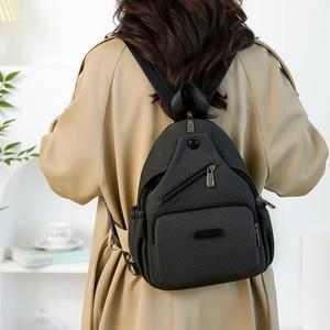 Vue détaillée d'un sac à dos gris foncé à texture tissée avec des poches zippées sur modèle
