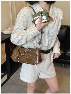 Detail der dunkelbraunen Tasche mit Polka-Dots, Herzanhänger und doppelten Klapptaschen