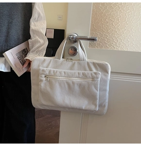 Detail of off-white corduroy laptop bag hanging on handle with textured front pocket