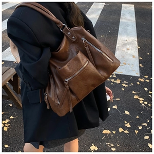 Detail of vintage brown PU leather shoulder bag with tassels and multiple zipper pockets