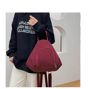Macro shot of burgundy plaid dumpling backpack with metallic circular zipper pull