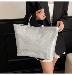 Detail of silver tote bag with snake skin texture and white printed TOTE BAG text