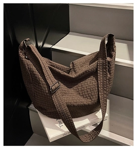 Detalle de bolso tote de lona a cuadros marrones con correa ajustable en escalera