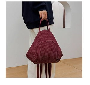 Detail of burgundy checkered dumpling bag with convertible backpack straps and handles