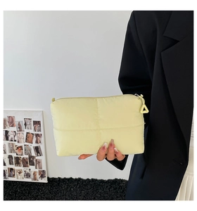 Close-up of beige quilted nylon handbag featuring a unique triangle zipper pull detail