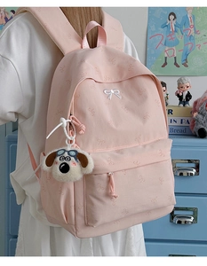 Detail of pink backpack with bow embroidery and cartoon dog charm on side zipper