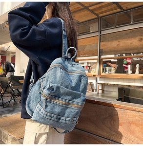 Détail d'un sac à dos en jean vintage avec broderie marguerite et poches zippées