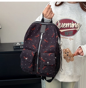 Détail du sac à dos noir avec motifs nœuds rouges, pois et porte-clé chien en peluche